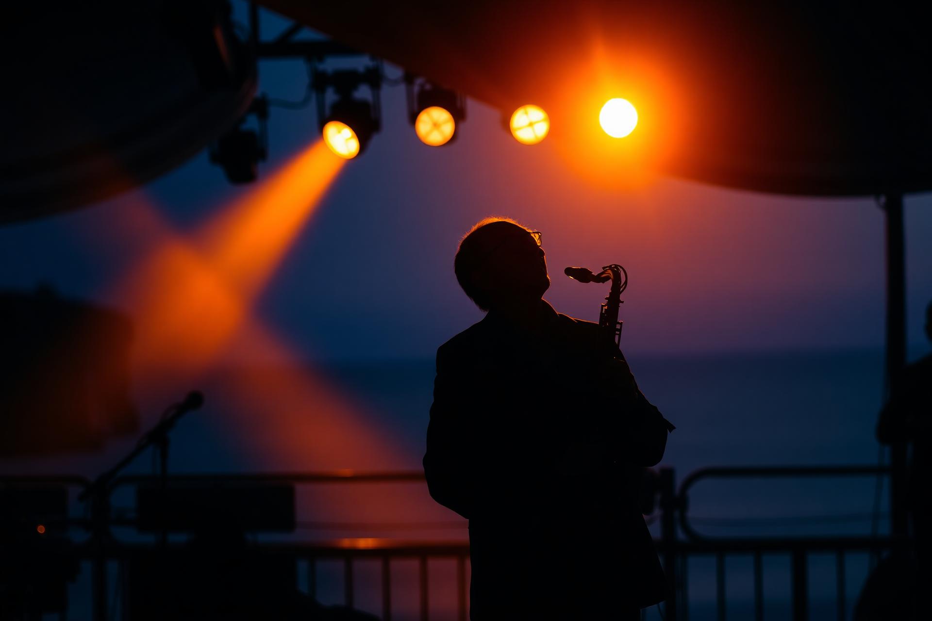 Saxofonista ao pôr-do-sol em palco à beira do Atlântico